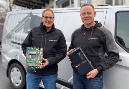 Zwei Personen stehen vor einem Transporter und halten Torsteuerungen in der Hand