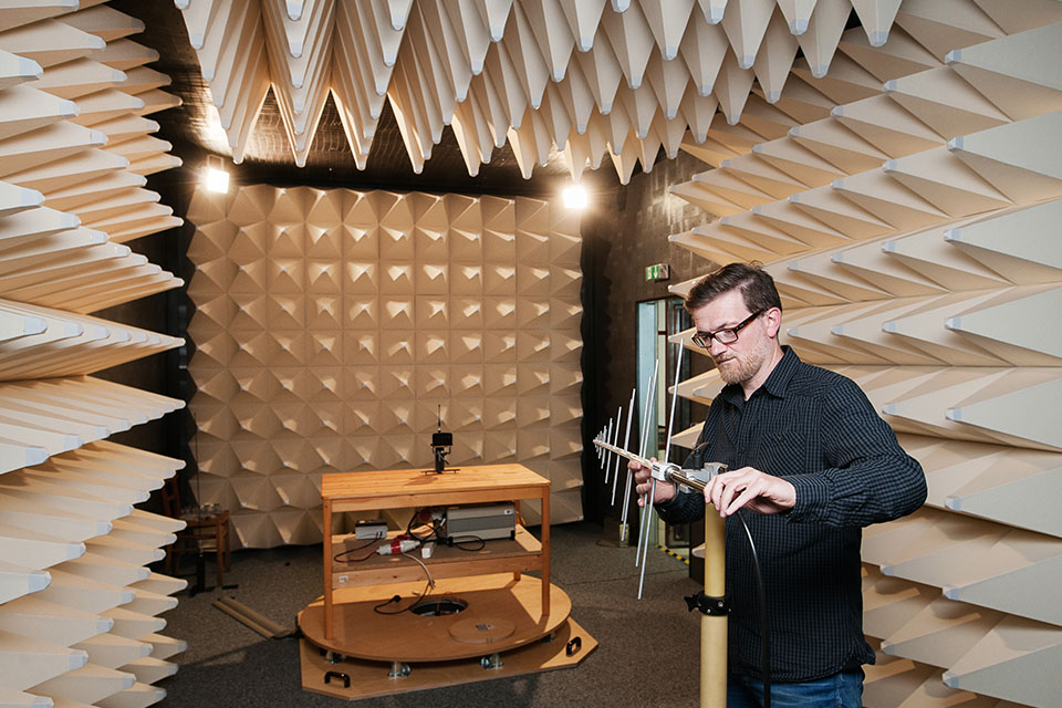 Person testet Stahlungsverhalten einer Antenne in einem Testraum